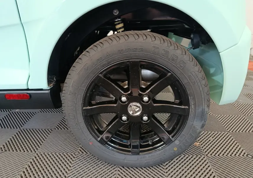 Gros plan sur la roue arrière droite noire brillante d'une Aixam Ambition Easy Chic thermique verte, année 2026.