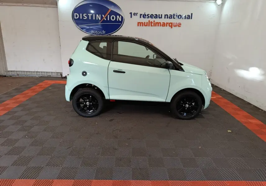Vue de profil côté droit d'une Aixam Ambition Easy Chic thermique 2026 vert clair avec toit noir et jantes noires.