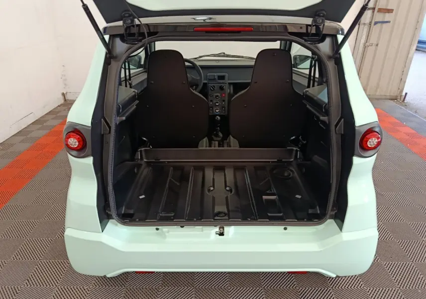 Vue arrière ouverte de l'AIXAM AMBITION Easy Chic thermique 2026 vert, montrant l'espace de coffre et les sièges noirs.