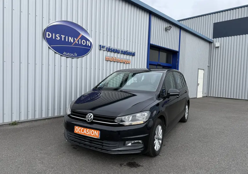 Volkswagen Touran noir 2017 vue 3/4 avant droit, avec plaque orange "OCCASION" devant un bâtiment gris.