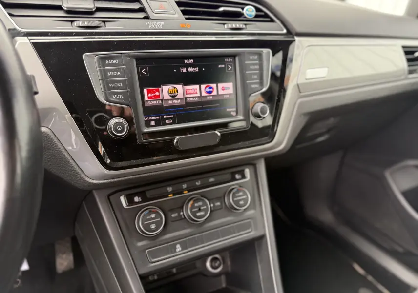 Vue intérieure du tableau de bord du Volkswagen Touran noir 2017, avec écran tactile central et commandes de climatisation visibles.