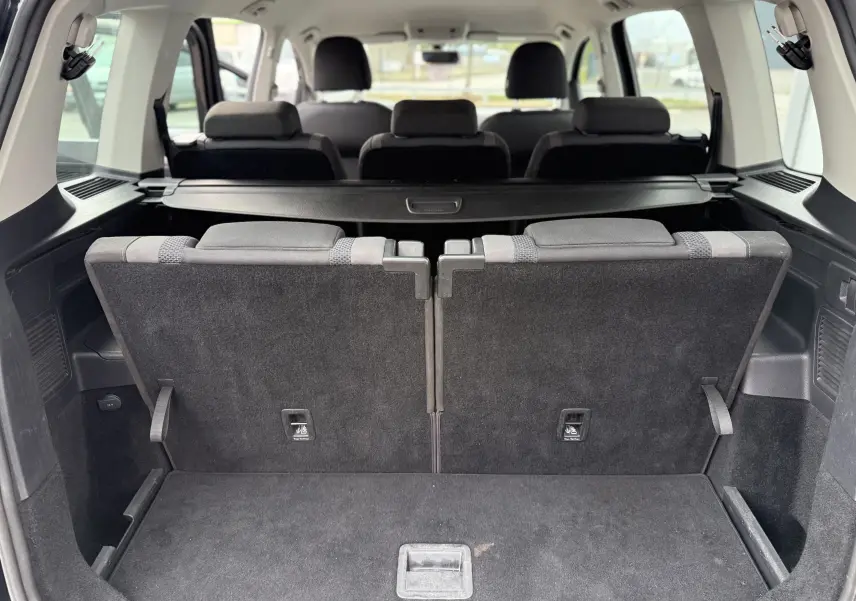 Vue arrière du coffre du Volkswagen Touran noir 2017, montrant les sièges arrière relevés et l'espace de chargement.