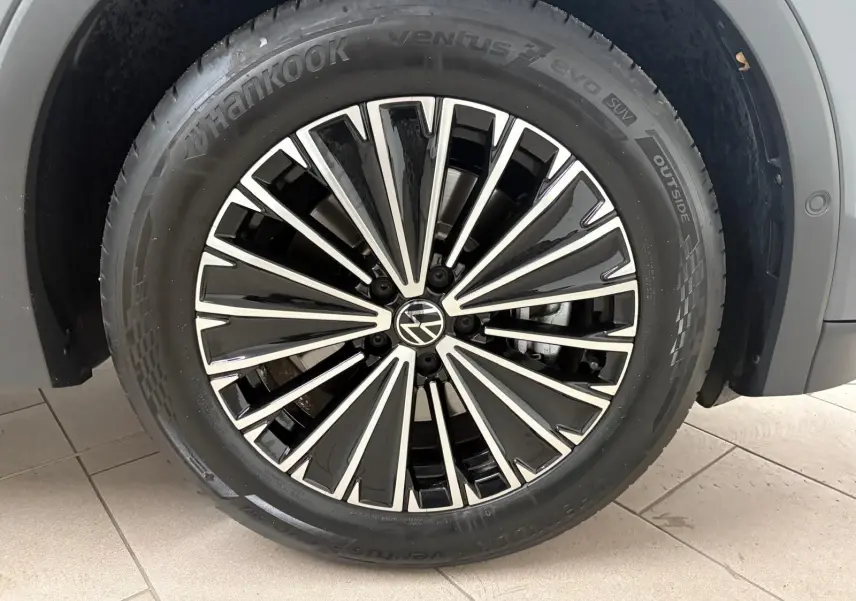 Gros plan sur la jante alliage bicolore du Volkswagen Tiguan Gris Dauphin, pneu Hankook visible sur sol carrelé.