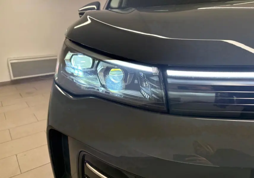 Gros plan sur le phare avant gauche du Volkswagen Tiguan 2025 gris Dauphin avec éclairage LED allumé.