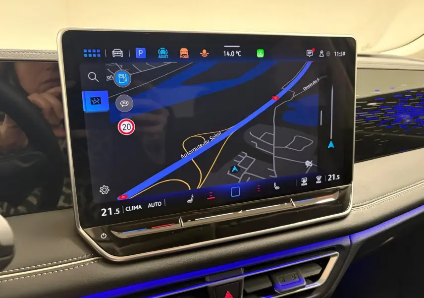 Écran tactile central du Volkswagen Tiguan 2025 avec navigation, ambiance lumineuse bleue et tableau de bord gris.