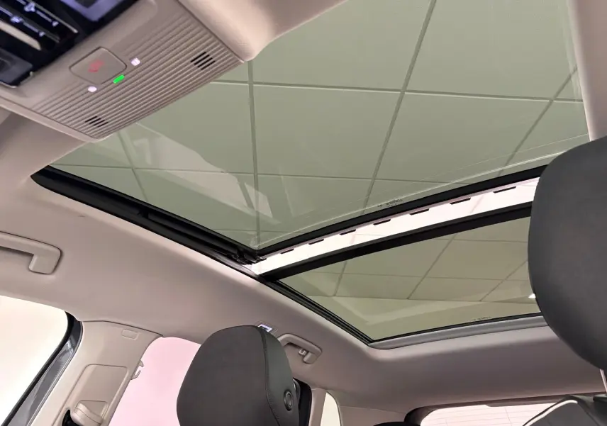 Toit panoramique ouvert vu de l'intérieur arrière du Volkswagen Tiguan gris Dauphin avec ciel de toit clair.