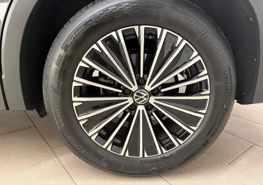 Gros plan sur la jante avant droite du Volkswagen Tiguan 2.0 TDI 150 DSG7 Elegance gris Dauphin avec logo VW central.
