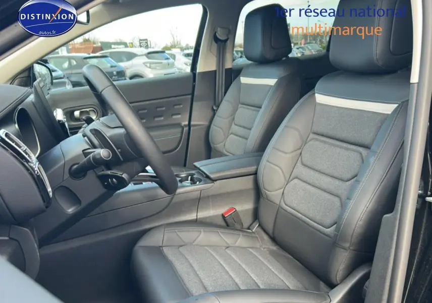 Vue intérieure côté conducteur du Citroën C5 Aircross noir, mettant en valeur les sièges en cuir et tissu gris avec accoudoir central.