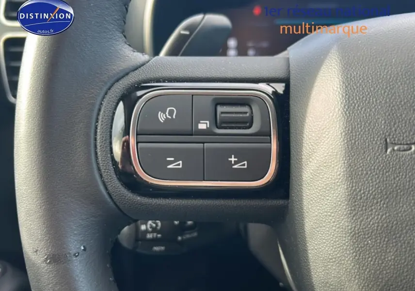 Gros plan sur les commandes multifonctions à gauche du volant cuir noir du Citroën C5 Aircross hybride 2025.
