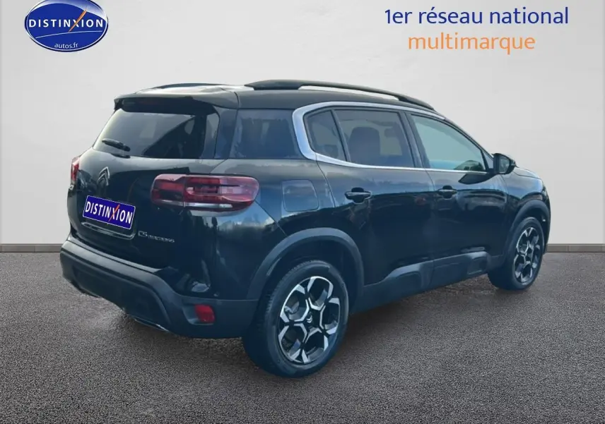 Vue 3/4 arrière droite d'un Citroën C5 Aircross noir avec jantes alu et barres de toit visibles.
