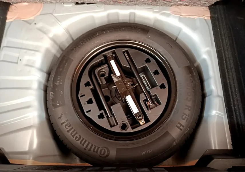 Vue en plongée sur la roue de secours et ses outils dans le coffre d'une Renault Clio Business gris clair 2020.