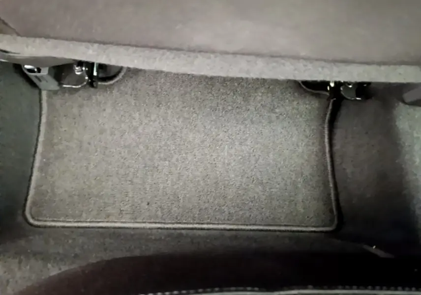 Vue rapprochée du tapis de sol gris sous le siège arrière d'une Renault Clio Business TCe 100 de 2020.