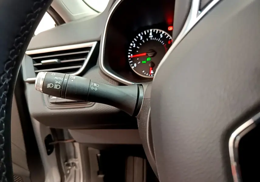 Gros plan sur le commodo d’éclairage à gauche du volant dans l’habitacle gris clair de la Renault Clio Business TCe 100 2020.