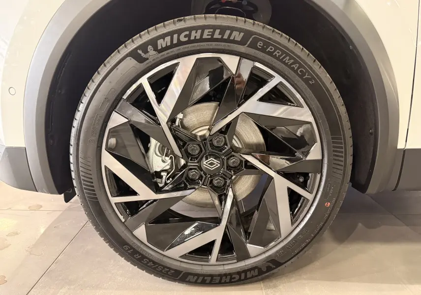 Gros plan sur la jante avant droite du Renault Captur E-Tech blanc nacré, avec un design noir et argenté et pneu Michelin.