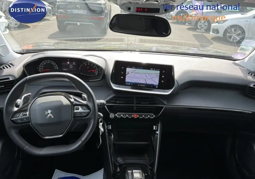 Vue intérieure avant du Peugeot 2008 noir perle métal 2022, tableau de bord moderne avec écran tactile et volant compact.