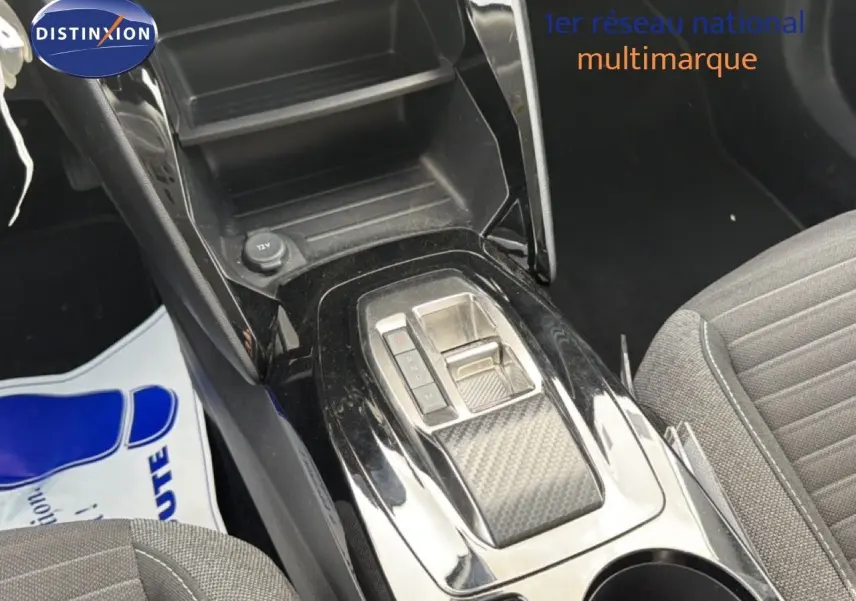 Vue rapprochée de la console centrale noire brillante avec levier de vitesses automatique et siège tissu gris côté droit.