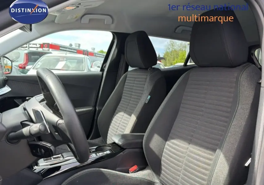 Vue intérieure côté conducteur du Peugeot 2008 2022, sièges tissu noir et console centrale brillante.