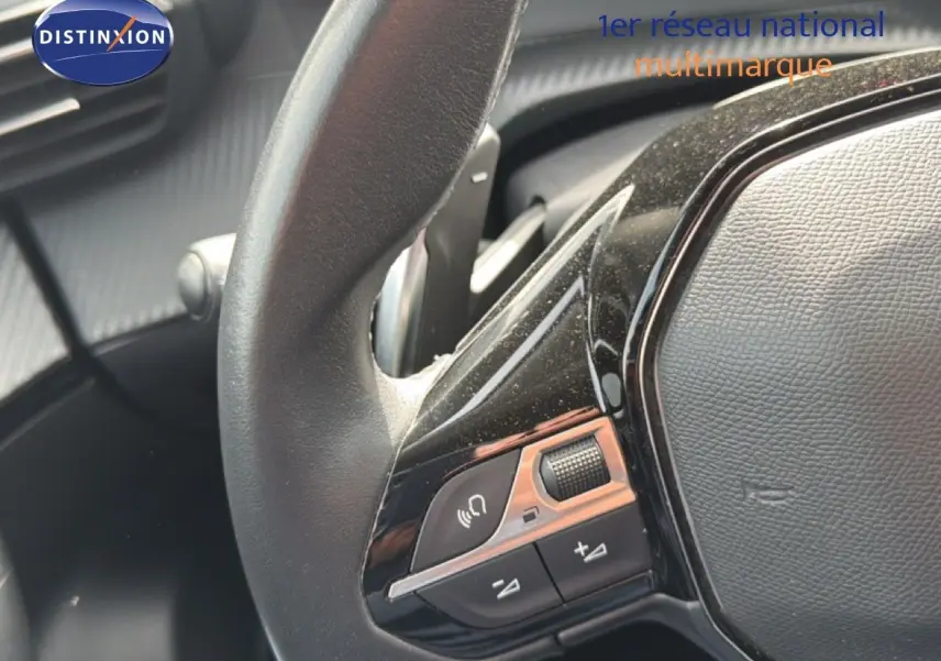 Gros plan sur le côté gauche du volant noir du Peugeot 2008 2022, avec commandes audio intégrées.