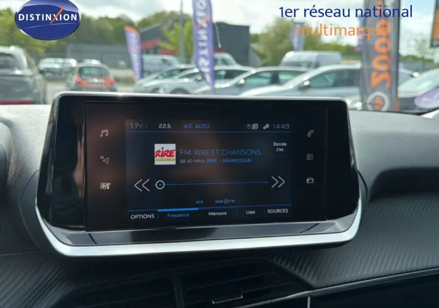 Écran tactile central du tableau de bord de la Peugeot 2008 noir perle métal, affichant une radio FM en extérieur.