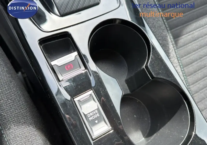Gros plan sur la console centrale noire perle métal du Peugeot 2008, avec bouton frein à main électronique et sélection drive mode.