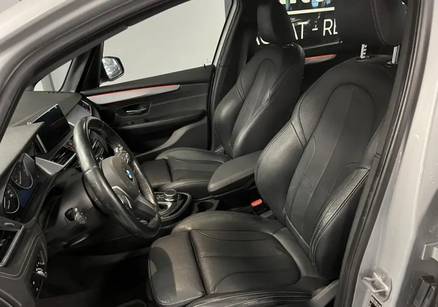 Vue intérieure côté conducteur de la BMW Série 2 225xe Active Tourer gris, sièges cuir noirs et tableau de bord moderne.