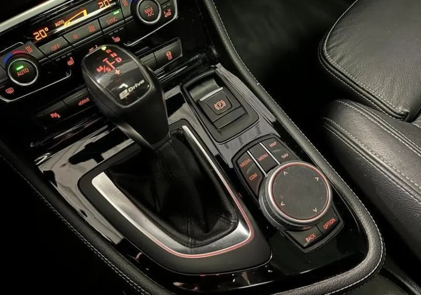 Gros plan sur la console centrale noire de la BMW Série 2 225xe M Sport avec levier de vitesse eDrive et commandes multimédia.