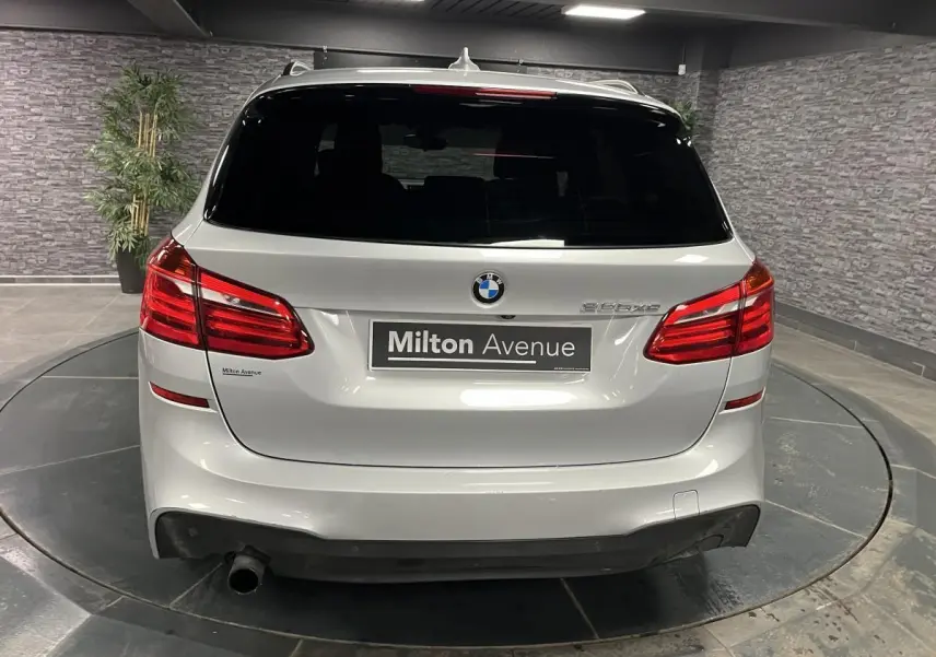 Vue arrière d'une BMW Série 2 225xe Active Tourer gris métallisé avec feux rouges et hayon fermé en intérieur.