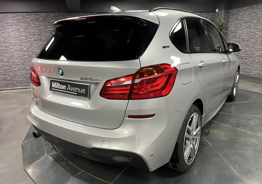 Vue 3/4 arrière droite d'une BMW Série 2 225xe Active Tourer gris métallisé avec jantes alliage et toit noir.