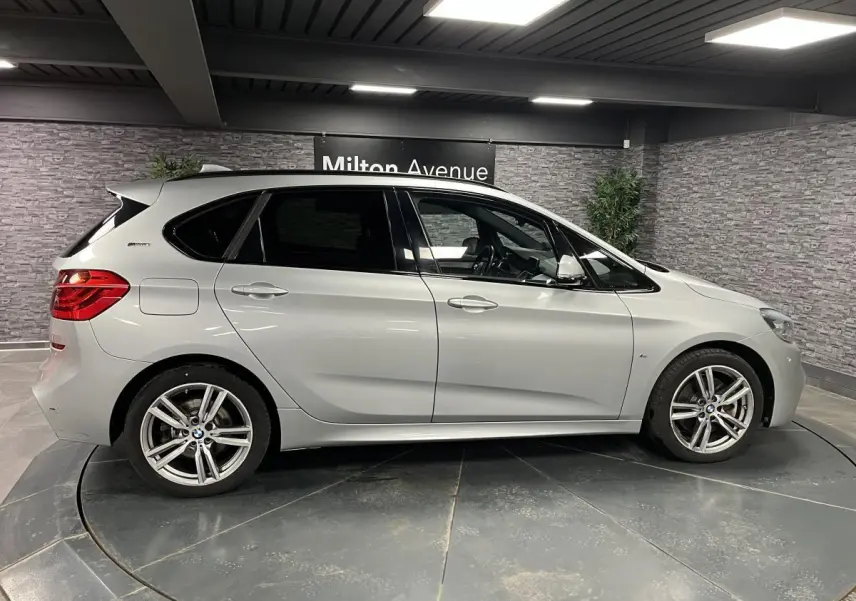 BMW Série 2 225xe Active Tourer gris vue de profil côté gauche en intérieur avec jantes alliage M Sport.