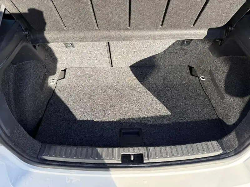 Coffre ouvert de la SEAT IBIZA 1.0 TSI 115cv FR blanc Nevada, montrant l'espace de rangement intérieur en tissu gris.