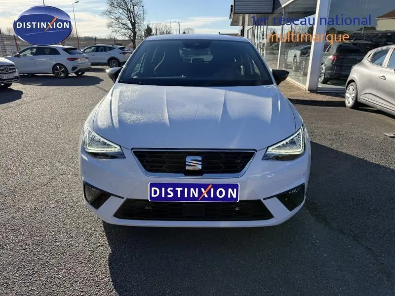 Vue frontale d'une SEAT Ibiza 1.0 TSI 115cv FR blanche Nevada métallisée avec calandre noire et phares LED allumés.