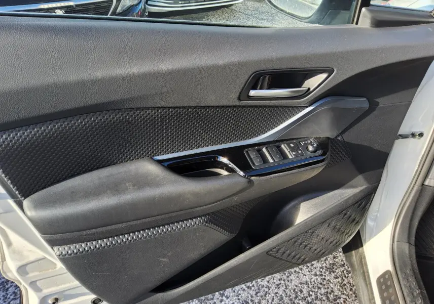 Vue côté gauche de la porte avant blanche nacrée du Toyota C-HR 2020 avec commandes électriques et garnitures noires texturées.