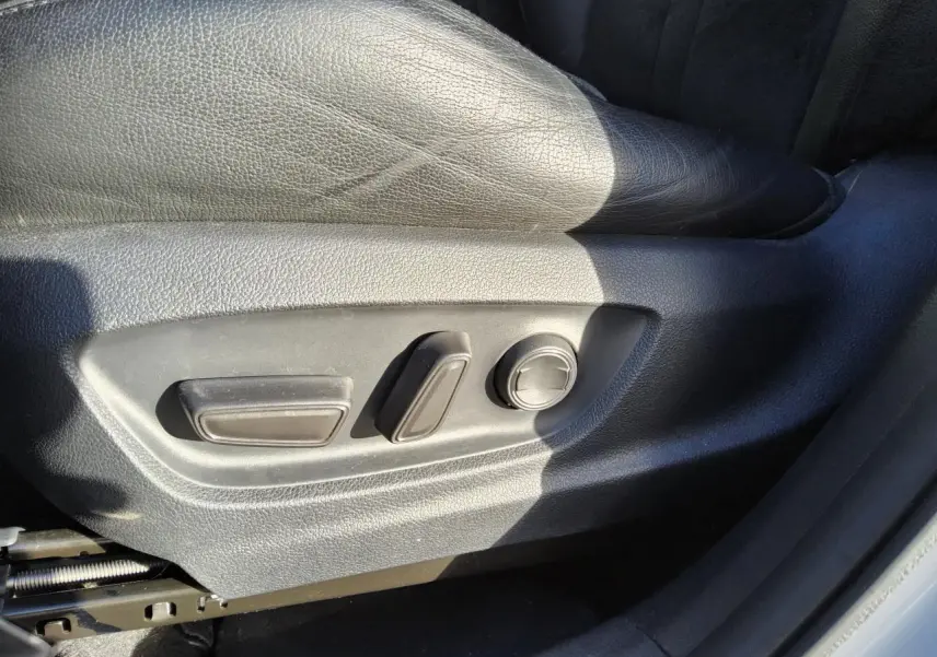 Détail des commandes de réglage manuel du siège conducteur en cuir noir dans un Toyota C-HR blanc nacré 2020.