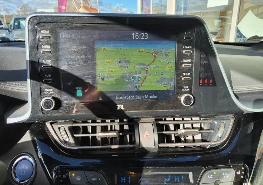 Vue rapprochée de la console centrale du Toyota C-HR blanc nacré, avec écran tactile de navigation et commandes climatisation.