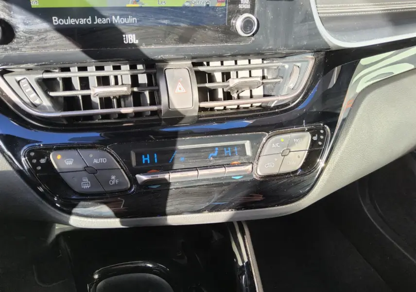 Vue rapprochée de la console centrale noire brillante du Toyota C-HR 2.0 Hybrid 2020 avec commandes climatisation digitale.