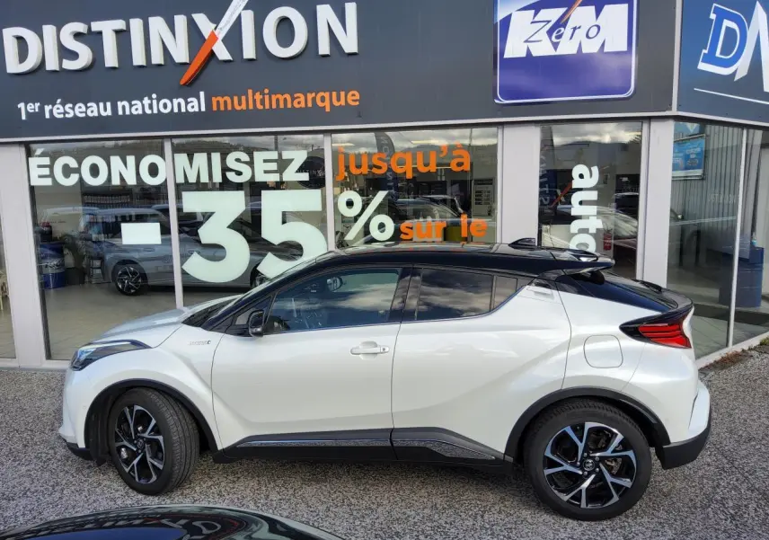Toyota C-HR blanc nacré vue de profil côté gauche avec toit noir et jantes alliage 18 pouces.