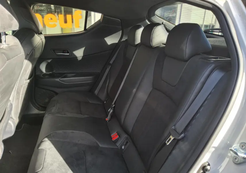 Vue intérieure côté arrière droit du Toyota C-HR blanc nacré 2020, montrant les sièges arrière en tissu noir et alcantara.