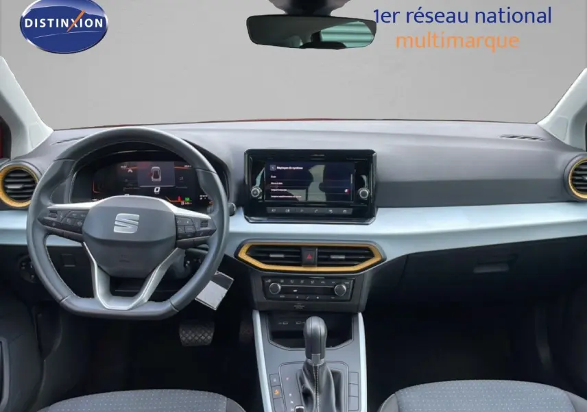 Vue intérieure frontale du tableau de bord du SEAT Arona rouge Désir Métal 2025 avec volant multifonction et écran tactile central.