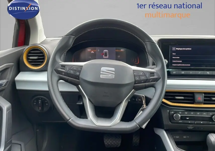 Vue intérieure centrée sur le volant cuir du SEAT Arona 2025, avec tableau de bord et détails jaunes autour des aérateurs.