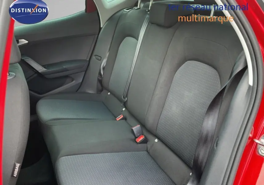 Vue intérieure sur la banquette arrière du SEAT Arona rouge désir métal, avec sièges en tissu noir et ceinture de sécurité visible.