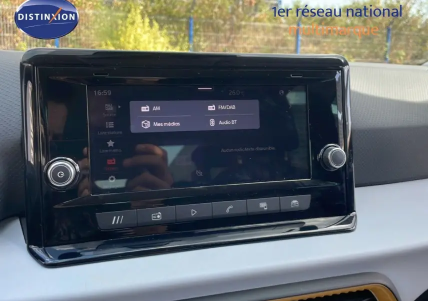 Écran tactile central du tableau de bord du SEAT Arona 2025, affichant les options audio avec reflet extérieur.