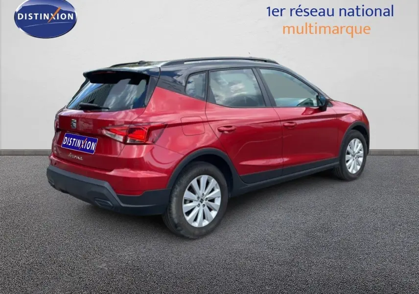 Vue 3/4 arrière droite d’un SEAT Arona rouge désir métal avec toit noir, jantes argent et détails noirs contrastants.