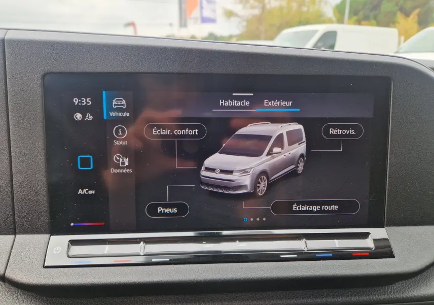 Écran tactile intérieur montrant une vue 3/4 avant d’un Volkswagen Caddy blanc avec options d’éclairage et pneus.