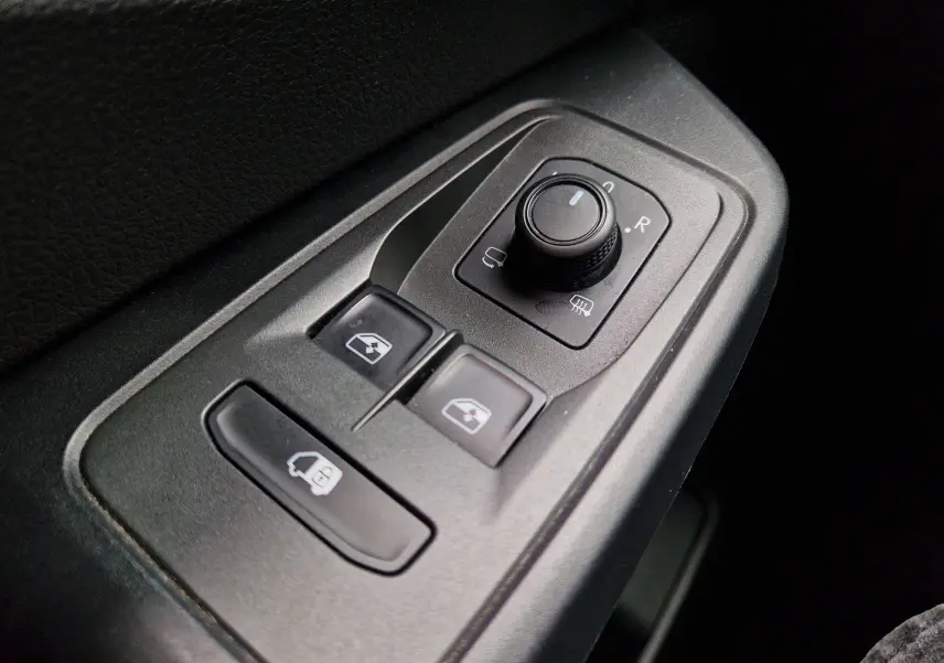 Gros plan sur les commandes de réglage des rétroviseurs et des vitres côté conducteur du Volkswagen Caddy Cargo blanc 2023.