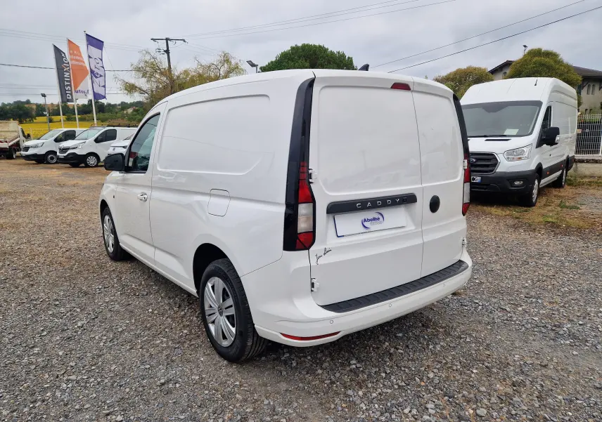Vue 3/4 arrière droite d’un Volkswagen Caddy Cargo blanc 2023 avec portes arrière pleines et feux verticaux noirs.