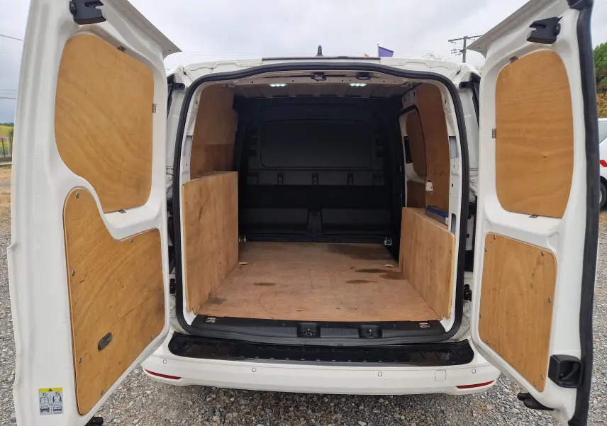 Vue arrière ouverte du Volkswagen Caddy Cargo blanc 2023, montrant l'intérieur de chargement avec revêtement bois.