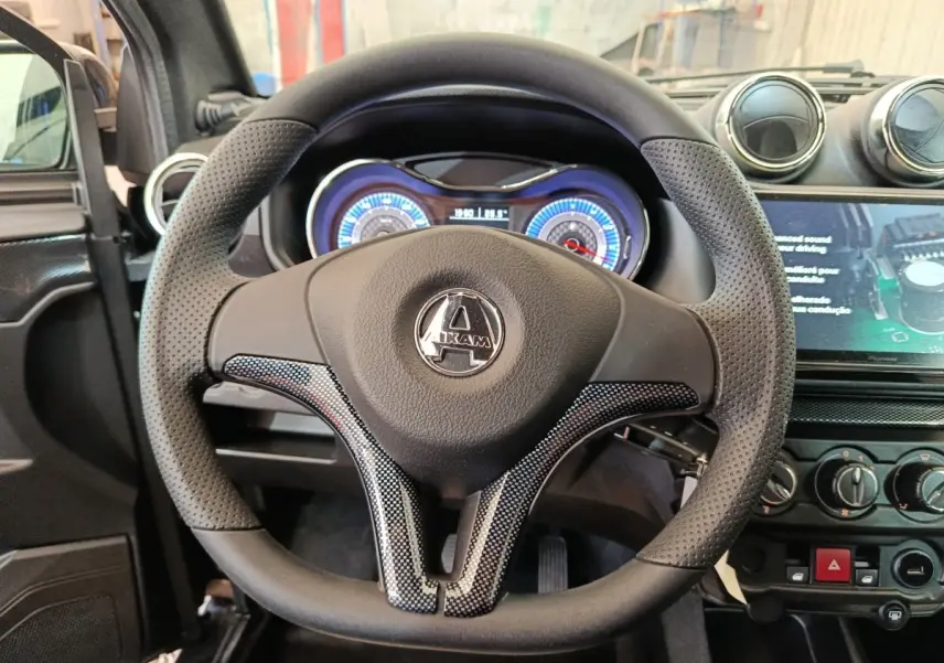 Vue intérieure centrée sur le volant noir perforé de l'AIXAM Ambition 0.5 City Coupe GTI avec tableau de bord lumineux.