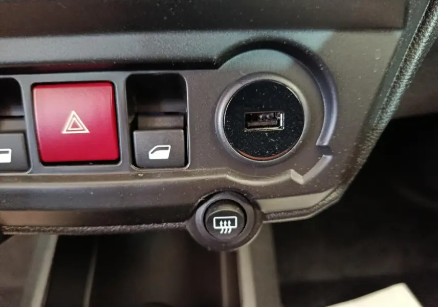Gros plan sur la console centrale de l'AIXAM Ambition 0.5 City Coupe GTI noire, montrant les boutons de commande et un port USB.