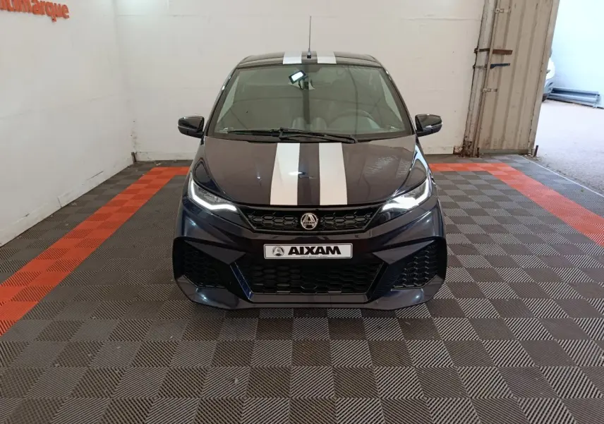 Vue avant d'une Aixam Ambition 0.5 City Coupe GTI noire avec bandes blanches sur le capot, phares allumés, en intérieur.