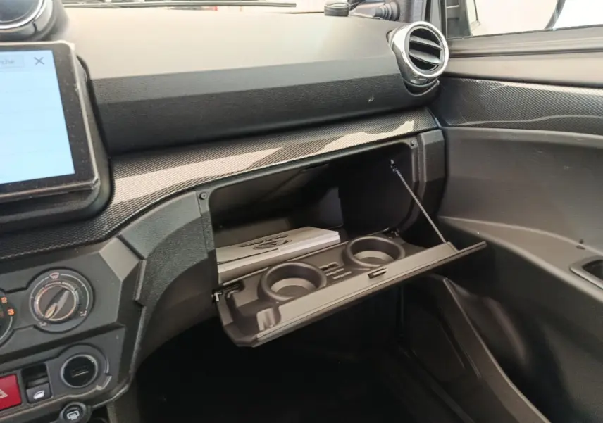 Intérieur de l'AIXAM Ambition 0.5 City Coupe GTI 2026, vue sur la boîte à gants ouverte avec porte-gobelets intégrés.